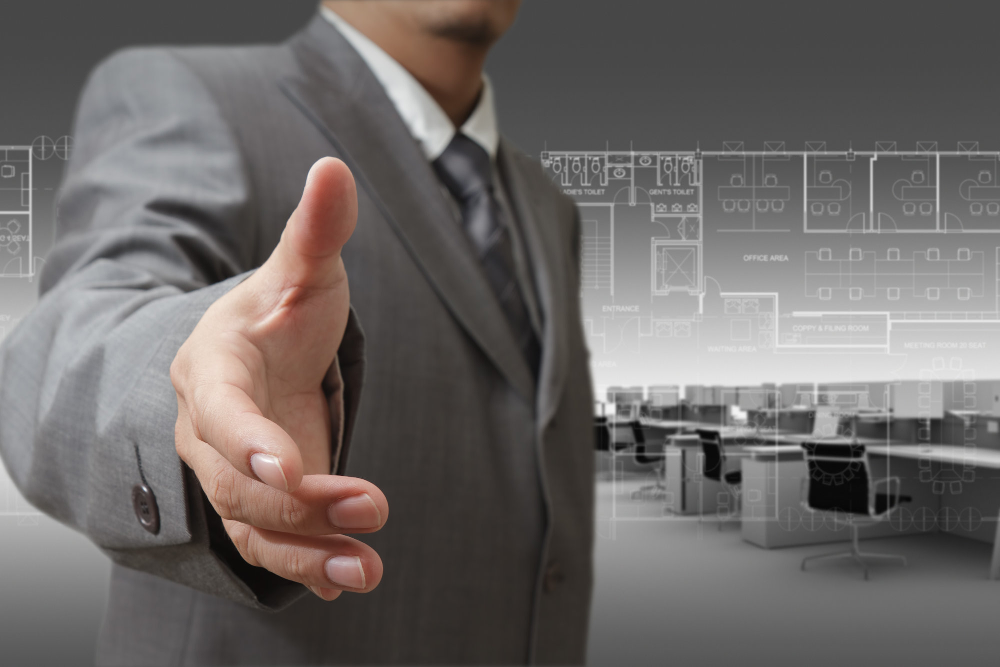 Man in gray suit reach hand towards the viewer